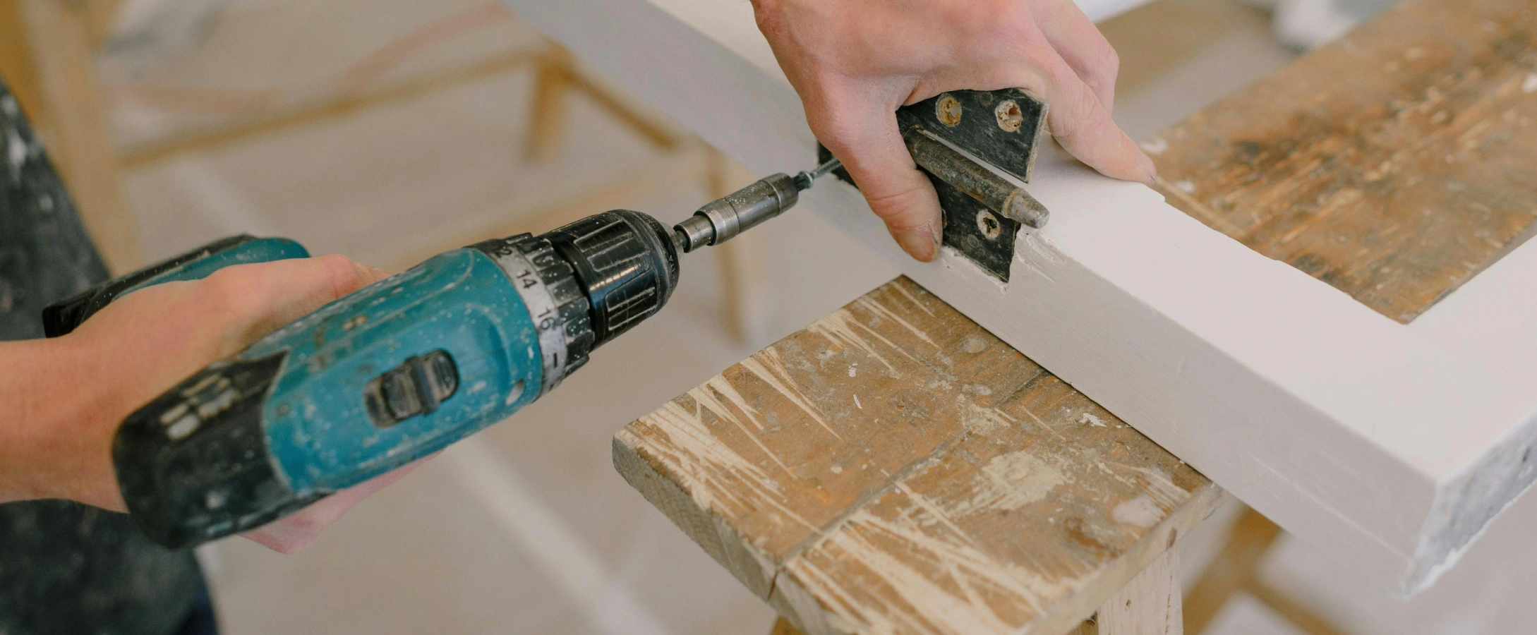 Person using a power drill to attach a hinge on a piece of wood, showcasing woodworking craftsmanship.