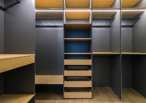Modern walk-in closet with wooden shelves and dark panels, ideal for organized bedroom storage solutions.
