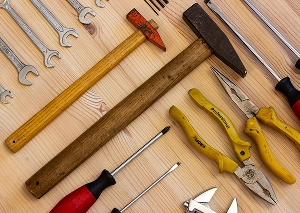 Various hand tools, including hammer, pliers, wrenches, and screwdrivers, laid out on a wooden surface for DIY projects.