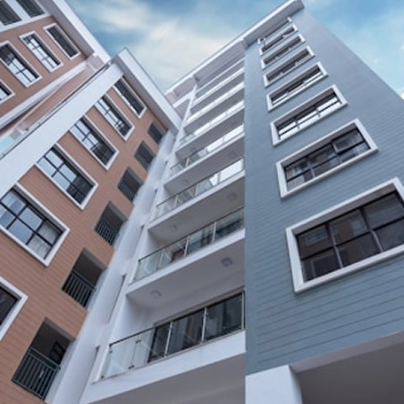 Modern high-rise residential buildings with balconies against a blue sky.