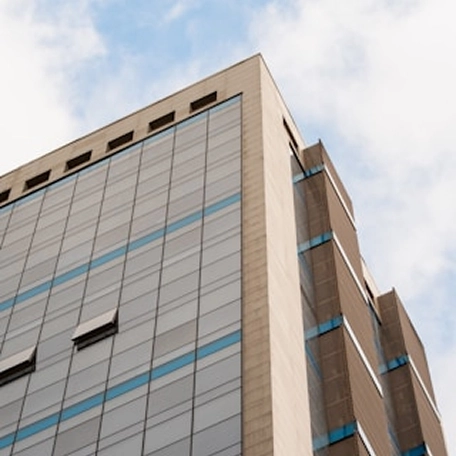 Modern office building exterior with blue glass windows against a partly cloudy sky. Urban architecture design.