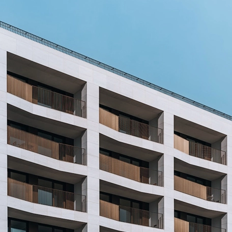 Modern apartment building with wooden balconies under a clear blue sky.
