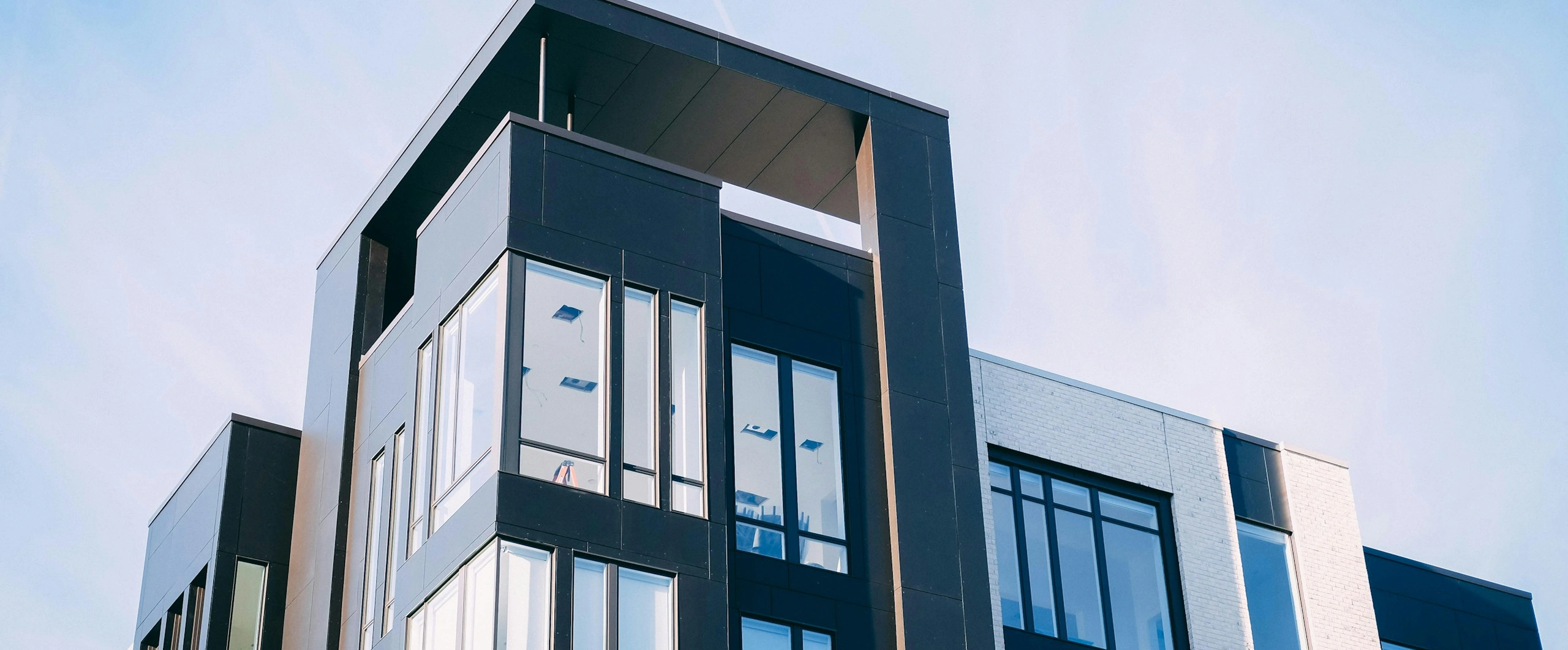 Modern building with large windows and sleek design against a clear sky background.