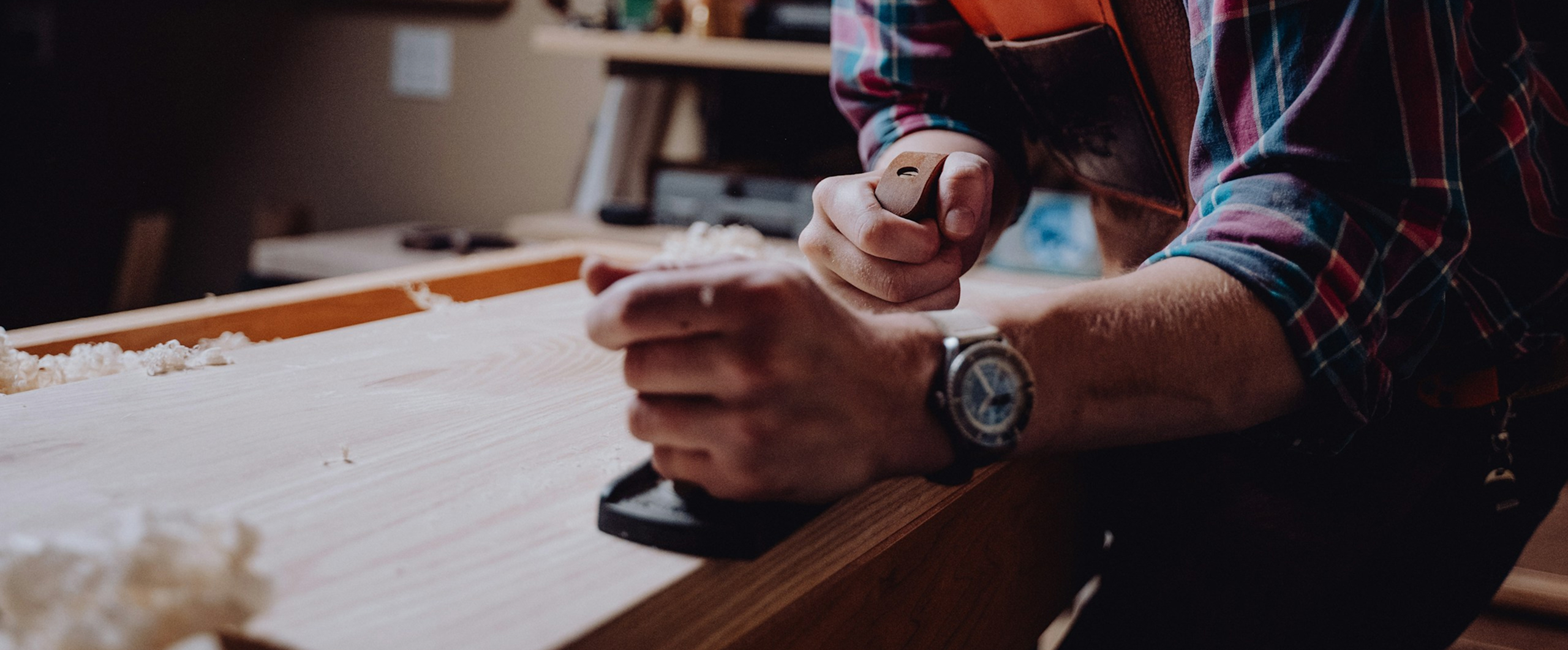 Skilled handyman using a hand planer on a wooden board during a carpentry repair project