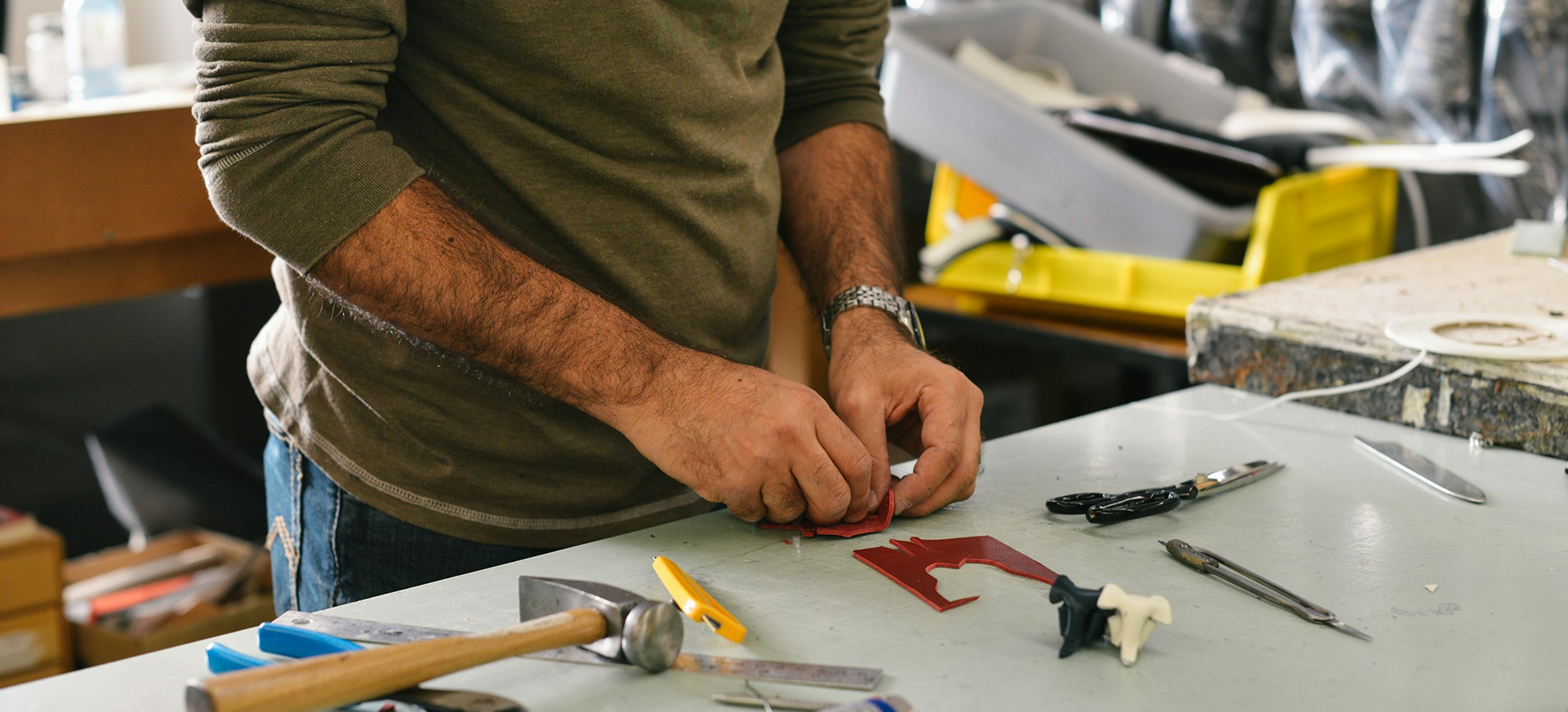 Handyman in Bellevue preparing materials at a workbench with essential repair tools including a hammer, utility knife, and pliers.