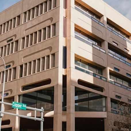 Modern architectural building with a textured facade and large windows, located at the intersection of Copper Avenue.